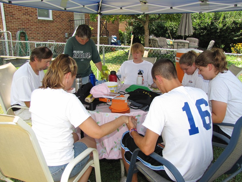 Youth praying around the table with those in need